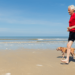 man running with dog on beach